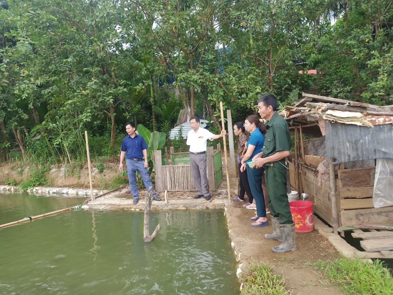 CCB Vi Xuân Điền (thứ nhất phải) hướng dẫn cán bộ địa phương tham quan mô hình kinh tế tổng hợp của gia đình